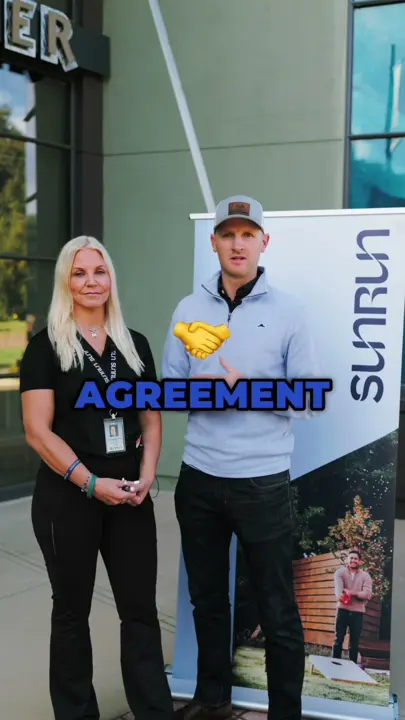 Two people standing beside a Sunrun banner